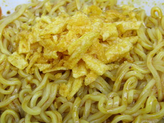 flat lay Close up  eat hot cooked fresh warm wavy textured red yellow brown gold color of mie mee goreng or fried noodle with potato chip krupuk kripik crackers new creation. thick like hair heap pile