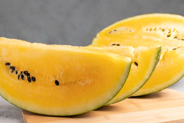 Sliced yellow watermelon on a wooden cutting board on a table