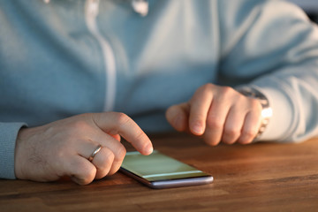 Close-up of male hands surfing internet on modern smartphone. Businessman searching information via special cellphone app. Social networks and modern technology concept