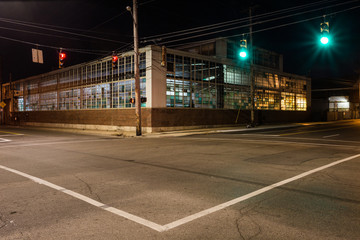 Street corner at night with vintage warehouse featuring multicolored windows and traffic lights