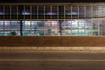 Multicolored windows on a vintage warehouse at night with empty street