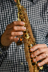 Naklejka premium soprano saxophone in hands on a black background