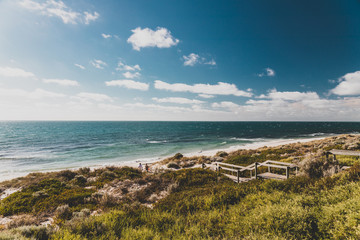 view of Cottesloe beach near Perth with thick vegetations and staircases leading to the sandy shore
