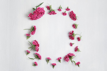 Floral arrangement with copy space. Template for greeting card or design. Frame of pink carnations on a white wooden background