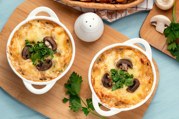 Casserole with chicken, mushrooms and cheese, known in Russia as julienne in white bowls with herbs, top view, flat lay