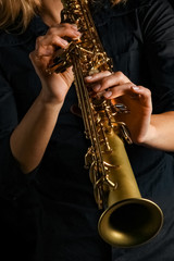 soprano saxophone in hands on a black background