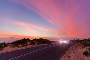Car traveling on scenic ocean drive at beautiful sunset