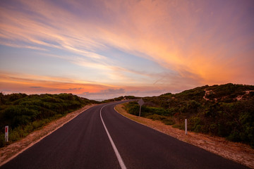 Fototapeta premium Scenic road winding into the distance near the ocean at beautiful sunset