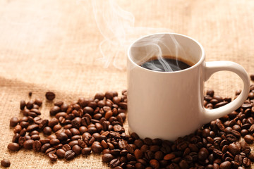 Roasted coffee beans in white cup on sackcloth