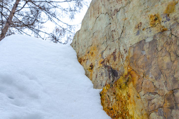 A piece of granite in winter under the snow.A large stone near the Winter day.