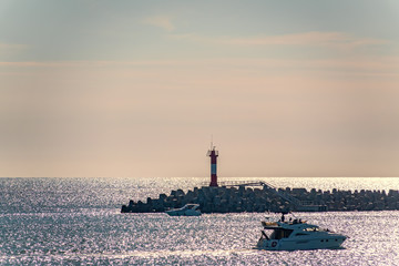 Clear sky and bright sunset over the sea with a breakwater and a lighthouse