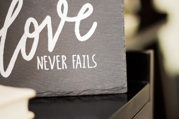 Grey Love never fails sign on a blurred background