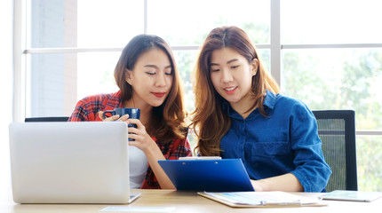 Two young asian women working with laptop computer at home office with happy emotion, Asia girls learning online education, working from home, small business, office casual lifestyle concept