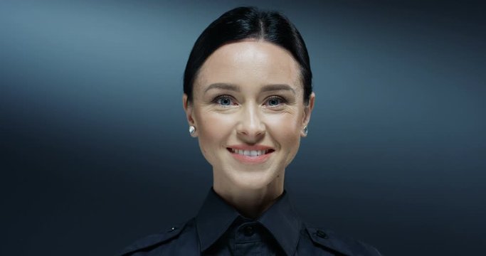 Close up of the young beautiful Caucasian brunette woman from police turning face to the camera and smiling cheerfully. Portrait.