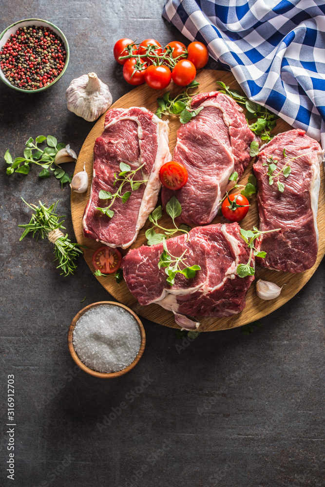 Wall mural Beef ribe eye steaks with rosemary oregano and tomatoes