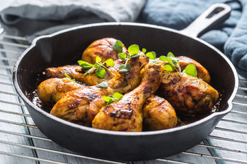 Roasted chicken legs in pan with herbs - close up