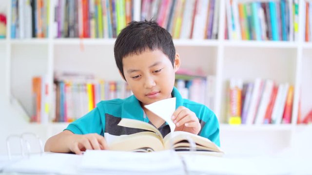 Bored preteen boy is studying with a book while yawning and sleeping in the library. Shot in 4k resolution