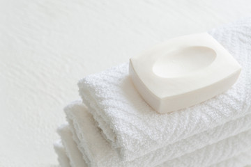 White cotton towel and soap on white background with copy space.