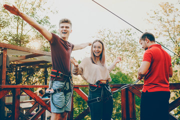 Beautiful young couple having fun laughing while preparing to jump with the rope slide while traveling.