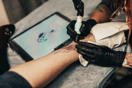 girl stuffs tattoo on woman leg closeup, sterility