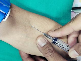 Close up nurse pricking needle syringe in the arm patient drawing blood sample for blood test, Nurse injecting with syringe to patient's arm drawing blood sample for blood test in hospital