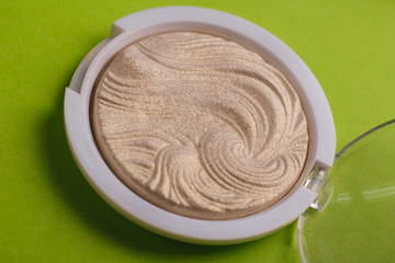 Cosmetics. Round highlighter on a green background. Face gloss