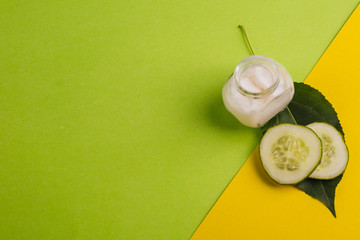 White cucumber cream on a yellow-green background. With leaves and fresh cucumber