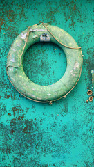 old blue faded life buoy hanging on rusty with cracked paint metal door