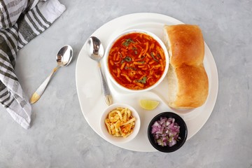 Spicy Misal Pav or usal Pav is a traditional snack or Chat food from Maharashtra, India. Served with chopped onion, lemon wedges and farsan. Selective focus with copy space