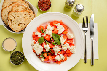 Healthy delicious salad with tomatoes and mozzarella on a green background