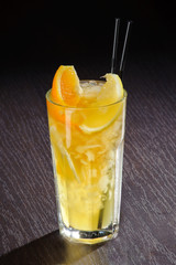 Fresh exotic cocktail with ice cubes and orange on a wooden table