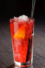 Fresh exotic cocktail with ice cubes and orange on a wooden table