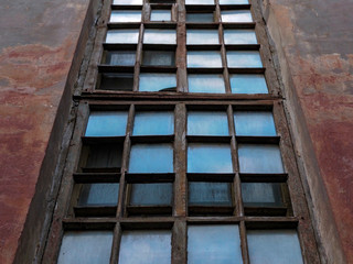 View of the old long window of the house. Geometric shapes of the window, background, broken glass.