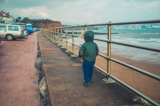 Little toddler walking by railings on the beach