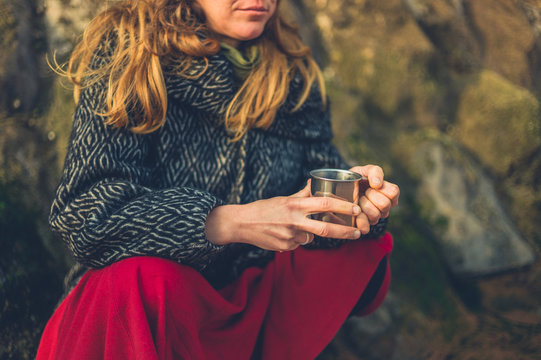 Cold woman with cup of tea on the beach in winter