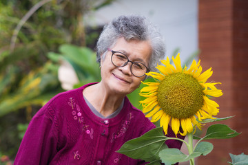 Senior woman with short gray hair, glasses, smiling and looking at the camera while standing beside...
