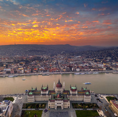 Obraz premium Budapest, Hungary - Aerial panoramic drone view of the Parliament of Hungary at sunset with beautiful dramatic golden clouds, Christmas tree and sightseeing boats on River Danube