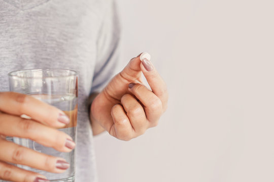 closeup woman hand taking pill with glass of water, healthcare and medical concept 