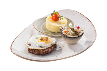 Fried egg with beefsteak, mashed potatoes and pickled cabbage on white plate isolated on white background