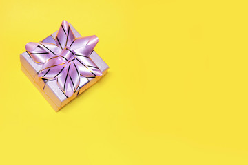 A gift with a beautiful ribbon isolated on yellow background