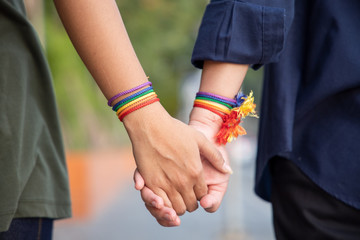 hand of LGBT women holding together with rainbow ribbon symbol; concept of LGBT pride, LGBTQ...