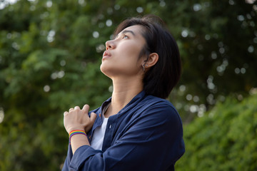 confident LGBT woman praying with rainbow ribbon symbol; concept of LGBT pride, LGBTQ people, lgbt rights wish, hope for equality, same sex marriage, sex preference diversity in modern society