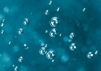 Bubbles of air on the smooth surface of blue water as an abstract background