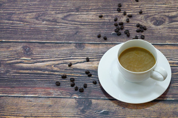 Cappuccino in white coffee cup on wooden table with dark roasted coffee bean