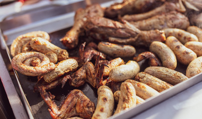 Grilled sausages and chicken legs on charcoal grill