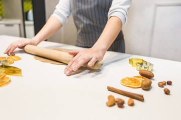 Young pretty woman prepares the dough and bakes gingerbread and cookies in the kitchen. Merry Christmas and Happy New Year.