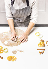 Young pretty woman prepares the dough and bakes gingerbread and cookies in the kitchen. She makes a star shape on the dough. Merry Christmas and Happy New Year.