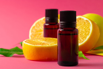 Citrus essential oil. Sliced citrus fruit and aroma bottles on pink background