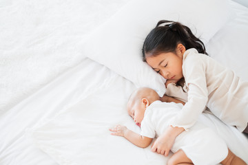 Asian cute girl sleep with baby on white bed