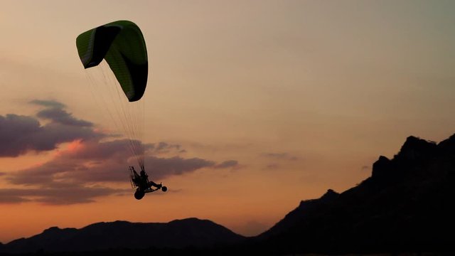 slow-motion of Paraglider flying against a sky at sunset over Khao Jeen Lae mountain in Lopburi, Thailand